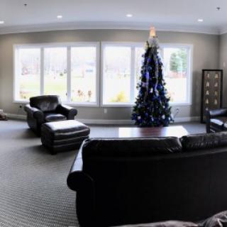 A cozy living room with a Christmas tree and comfortable seating.