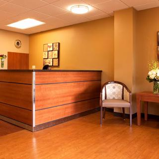 A warmly lit reception area with a wooden desk and seating.