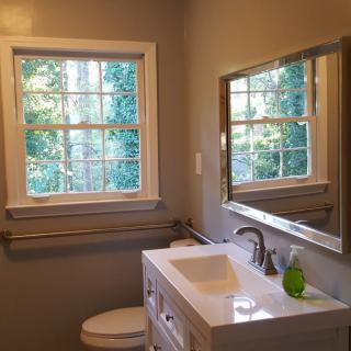 A well-lit bathroom with a large window, modern sink, and mirror.