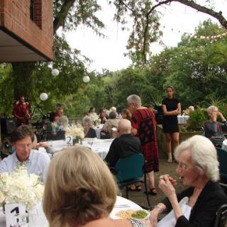 Guests enjoying an outdoor dinner party in a lush garden setting.