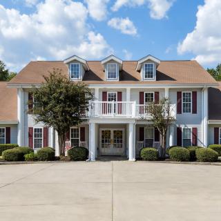 A colonial-style residential house with a spacious front driveway and elegant architecture.