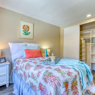 A cozy bedroom with colorful bedding and a neatly organized open wardrobe.