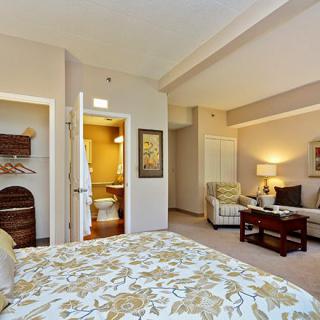 A cozy bedroom with elegant decor, featuring a bed, sofa, and warm lighting.