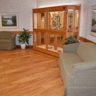 A cozy lobby area with sofas, wood flooring, an aquarium, and decorative plants.