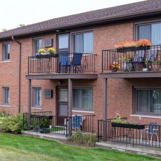 A brick apartment building with balconies and a green lawn.