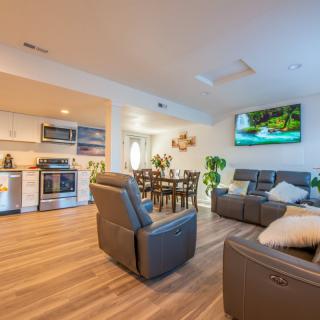 A modern open-concept living space featuring a kitchen, dining area, and comfortable seating with recliners and a flat-screen TV.