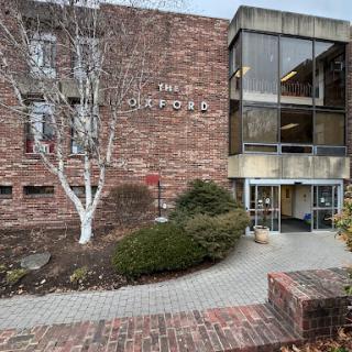 A view of a modern brick building featuring large glass windows and landscaped surroundings.