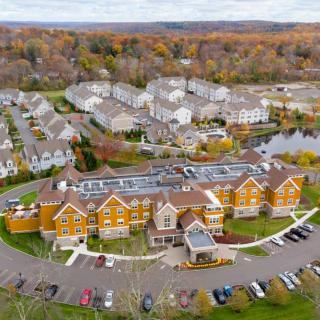 Aerial view of a residential complex surrounded by autumn foliage, featuring buildings with rooftop solar panels and a central parking lot.