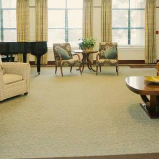 A spacious living room featuring a piano, sofa, and elegant chairs arranged around a coffee table.
