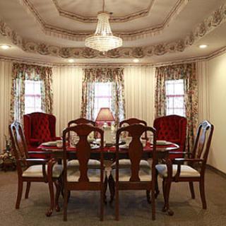 A traditional dining room with a wooden table and upholstered chairs under a chandelier.