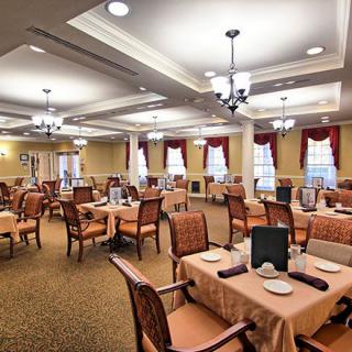 An elegantly designed dining area with neatly arranged tables and chairs, illuminated by chandeliers.