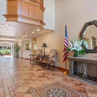 A spacious lobby area featuring seating, decorative floor tiles, a mirror, and an American flag.