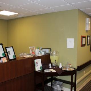 A welcoming reception area with a refreshment station, featuring green walls and various framed documents.