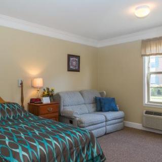 A cozy bedroom with a bed, couch, and warm lighting.