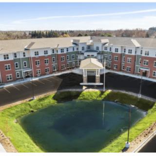 Aerial view of a residential building complex with a central pond.