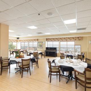 A spacious dining room with several tables and chairs, featuring large windows for natural light.