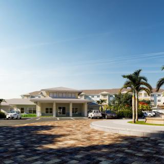 A sunny day view of a building entrance surrounded by palm trees.
