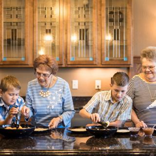 Family members of different generations cooking together in the kitchen.