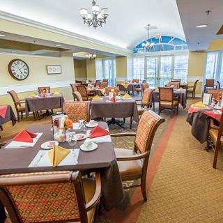 A beautifully set dining room with multiple tables and chairs, featuring elegant tableware and a welcoming atmosphere.