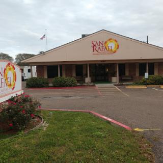 A view of a restaurant with a prominent sign, set against a cloudy sky.