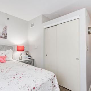 A cozy bedroom with a bed, a side table, and a closet.