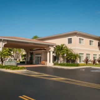A modern building with a covered entrance and palm trees lining the driveway.