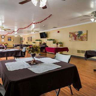 A cozy dining room decorated with flowers and set tables, ready for guests.