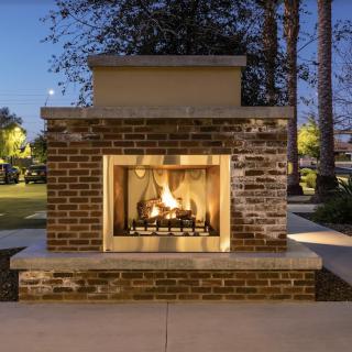 A cozy outdoor brick fireplace glowing warmly in the evening.