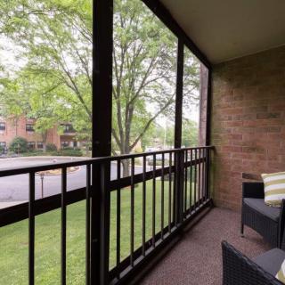 A cozy balcony with outdoor seating overlooking a green landscape.