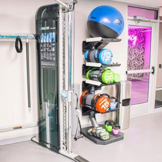 A gym corner with exercise and medicine balls neatly stacked on a rack.