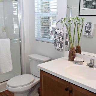 A modern bathroom with a glass shower, wooden cabinet, and decorative vases on the sink.