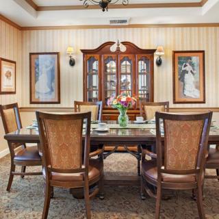A traditional dining room with a wooden table and chairs, complemented by a china cabinet and decorative paintings on the walls.