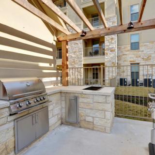 Outdoor grill area with a stone counter and pergola in an apartment complex.