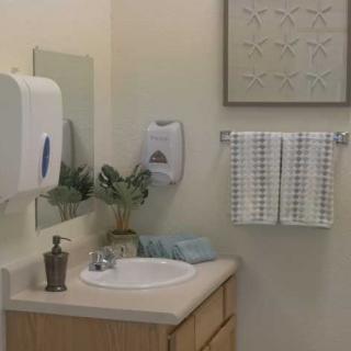 A tidy bathroom corner with a sink, mirror, and neatly hung towels.