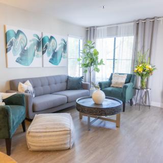 A modern living room with a gray sofa, teal armchairs, and stylish decor.