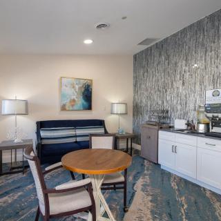 A modern waiting room featuring stylish furniture, artwork on the wall, and a convenient coffee station.