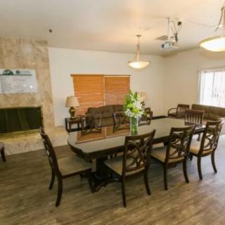 A well-decorated dining room with a large table, chairs, a fireplace, and floral centerpiece.