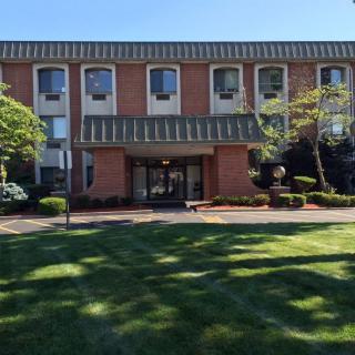 A three-story brick building with a well-maintained lawn and trees in front.