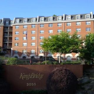 A view of a multi-story brick residential apartment building with trees in front.