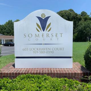 Somerset County sign stands prominently on a brick base, set against a backdrop of greenery and clear blue sky.