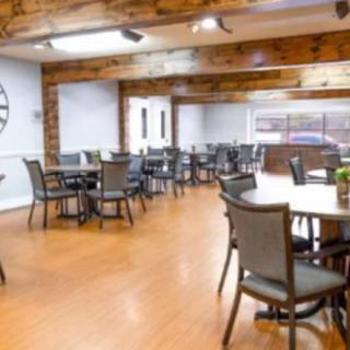 A spacious dining area with neatly arranged tables and chairs, featuring a wooden floor and modern decor.