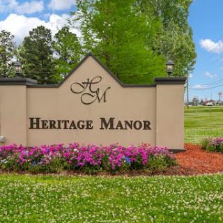 Welcome to Heritage Manor, a beautiful residential community surrounded by lush greenery and vibrant flowers.