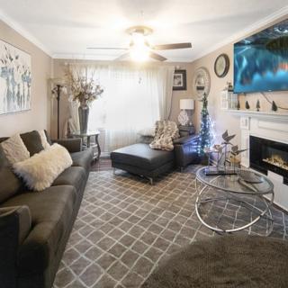A cozy living room with a modern sofa, coffee table, and a fireplace, featuring tasteful decorations and a flat-screen TV mounted above the mantel.