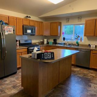 A modern kitchen with wooden cabinets and an island counter, featuring stainless steel appliances.