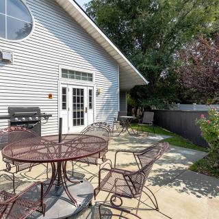 A spacious outdoor patio with metal furniture and a barbecue grill beside a house.