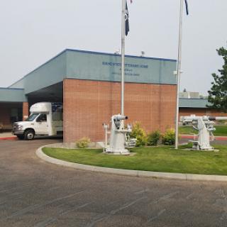 Exterior view of a facility with a vehicle parked in front and flagpoles on display.