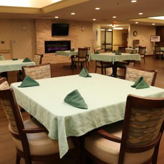 A well-arranged dining area featuring tables with green napkins in a warm and inviting environment.