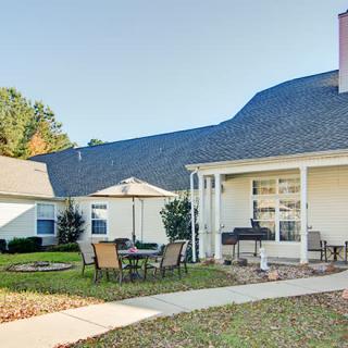 A cozy backyard with a patio and outdoor furniture, surrounded by well-maintained lawns and gardens.