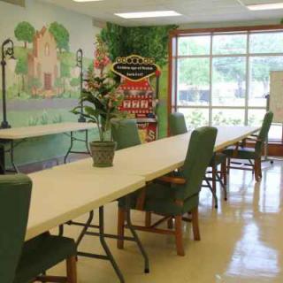 A well-lit meeting room with long tables, green chairs, and decorative wall art.