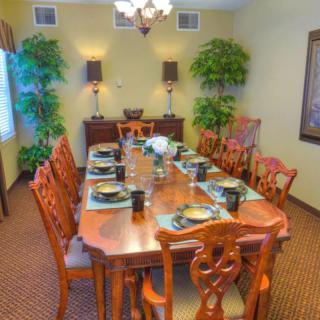 A well-decorated dining room with a long wooden table set for dinner.